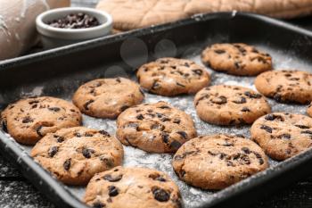 Tasty cookies with chocolate chips on baking tray�