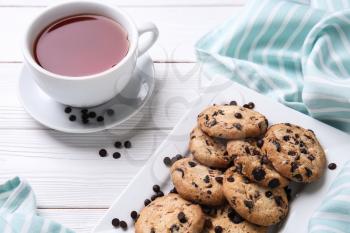 Tasty cookies with chocolate chips and cup of tea on white wooden table�