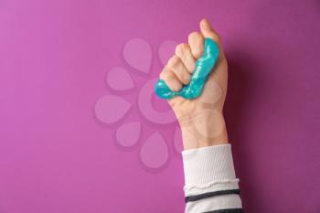 Female hand with anti-stress plasticine on color background�