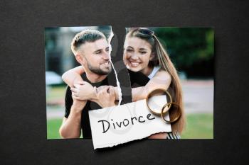 Torn photo of happy couple with rings on dark background. Concept of divorce�