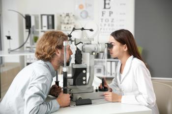 Ophthalmologist examining young man in clinic�