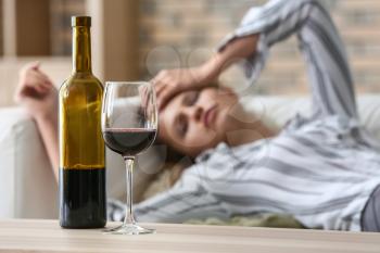Glass and bottle of wine on table of drunk woman�