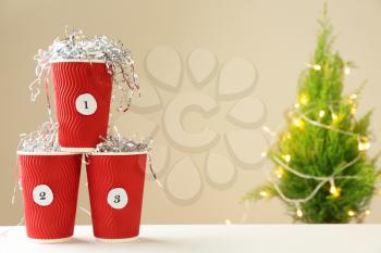 Paper cups with numbers on table. Christmas celebration�