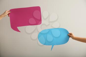 Female hands with blank speech bubbles on light background�