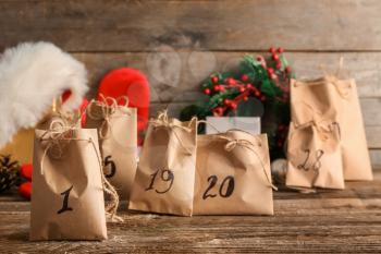 Paper bags with Christmas gifts and drawn numbers on wooden table�