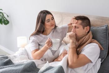 Woman taking care of her husband ill with flu at home�