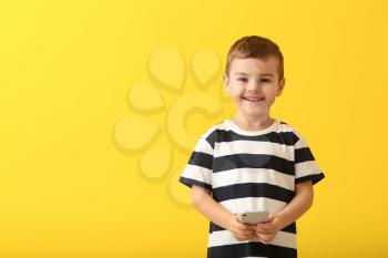 Cute little boy with smartphone on color background�