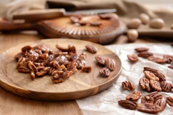 Candied pecan nuts on wooden plate�