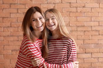 Portrait of happy mother and daughter on brick background�