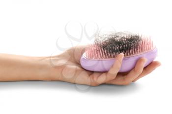 Female hand holding brush with fallen down hair on white background�