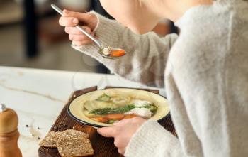 Woman eating tasty soup at table�