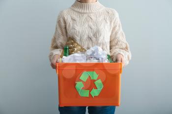 Woman holding box with trash on grey background. Recycle concept�
