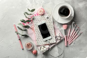Composition with mobile phone, cup of coffee and female items on grey background�