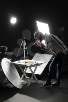 Young woman taking picture of tasty pasta in professional photo studio�