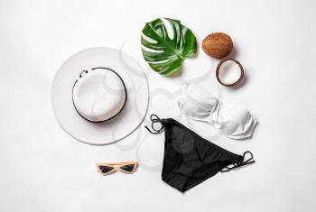 Female swimsuit with accessories, tropical leaf and coconut on white background�