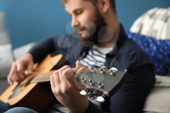 Bearded man playing guitar at home�