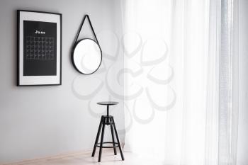 Interior of light room with calendar and mirror on wall�