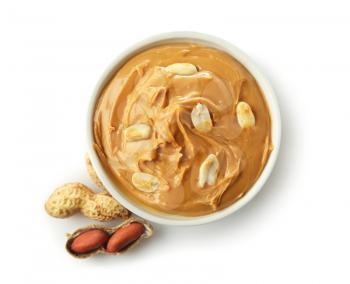 Tasty peanut butter in bowl on white background�