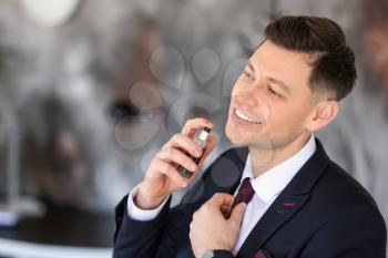 Handsome businessman with bottle of perfume indoors�