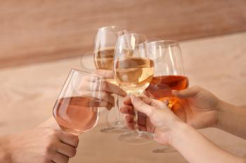 Women clinking glasses with tasty wine on wooden background�
