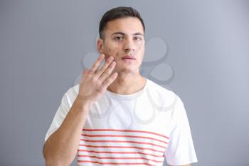 Portrait of young man with acne problem on grey background�