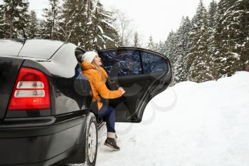 Young woman getting out of car at snowy winter resort�