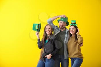 Young people in green hats on color background. St. Patrick's Day celebration�