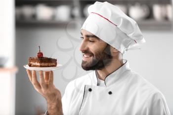 Male confectioner with piece of tasty chocolate cake in kitchen�