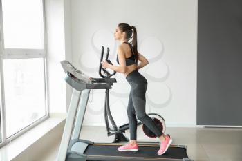 Sporty young woman on treadmill in gym�
