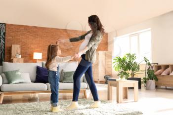 Pregnant mother with little daughter dancing at home�