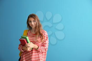 Schoolgirl with books on color background�