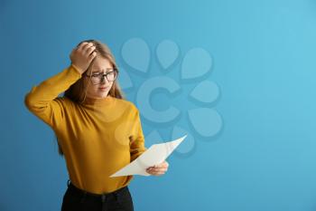 Displeased girl with results of school test on color background�