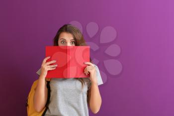Schoolgirl with book on color background�