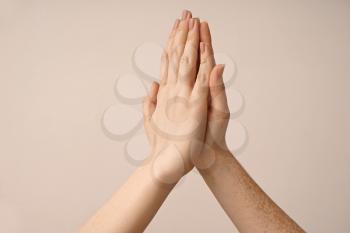 Young women touching palms on light background�