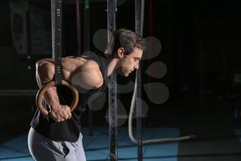 Young sporty man training with gymnastics rings in gym�