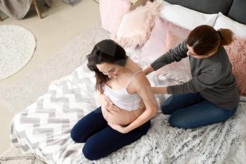 Doula massaging pregnant woman at home�