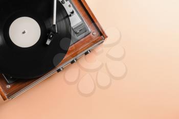 Record player with vinyl disc on color background�