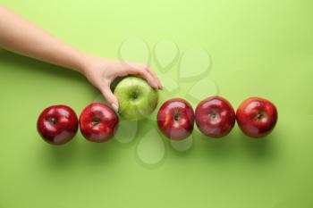 Female hand with tasty apples on color background. Concept of uniqueness�