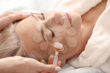Mature woman receiving face massage in beauty salon�