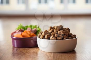 Bowls with dry and fresh pet food on floor�