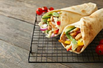 Cooling rack with tasty doner kebab on wooden table�