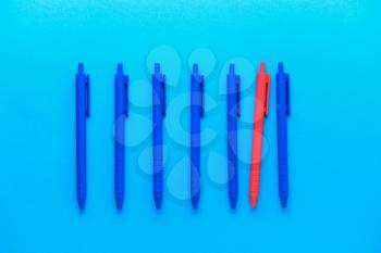 Red pen among blue ones on color background. Concept of uniqueness�