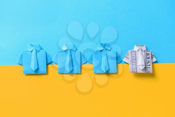 Origami shirt made of dollar banknote among paper ones on color background. Concept of uniqueness�