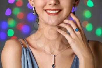 Young woman with beautiful jewelry against defocused lights, closeup�