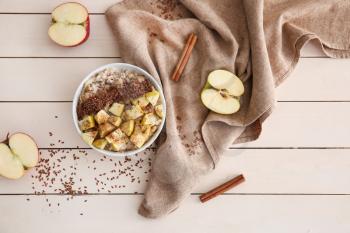 Bowl with tasty sweet oatmeal on wooden table�