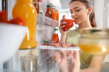 Woman taking food out of fridge at home, view from inside�