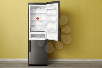 Big modern fridge near color wall�