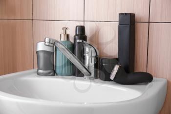 Electric shaver with cosmetics on sink in bathroom�
