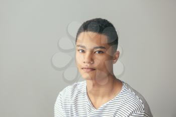 Sad African-American teenage boy on grey background�