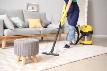 Female janitor with vacuum cleaner in room�